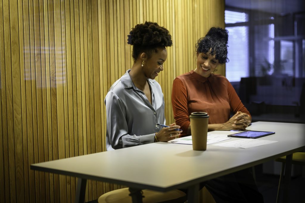 Two women sitting at a rectangular table, looking at papers