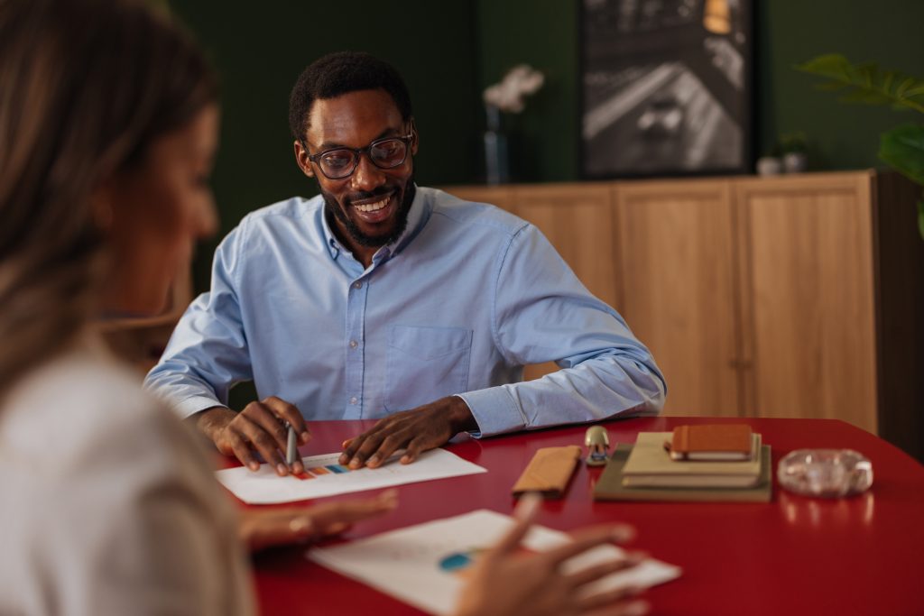 Man and woman sitting at a red table looking at graphs