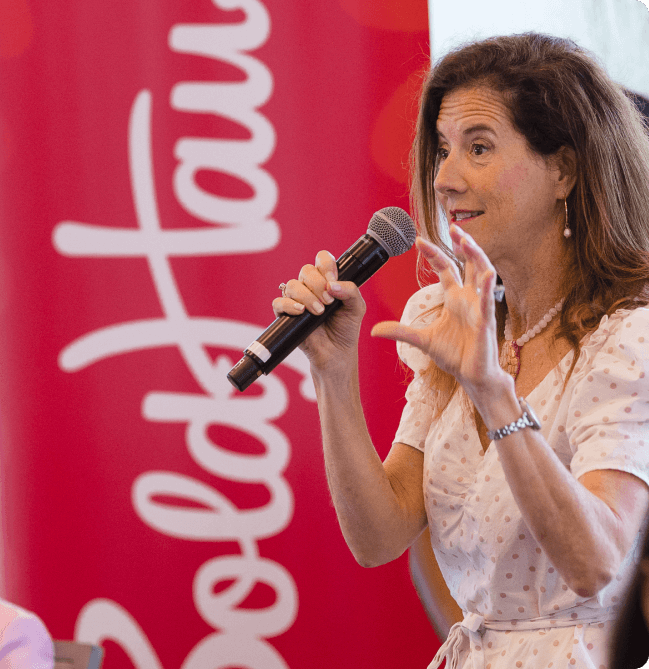 Confident businesswoman in a white suit speaking on stage at a BoldHaus event