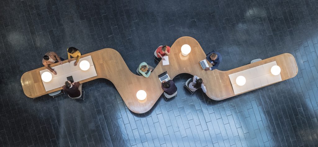 Birds eye view of a zigzag wooden table with a dark blue tiled floor underneath it