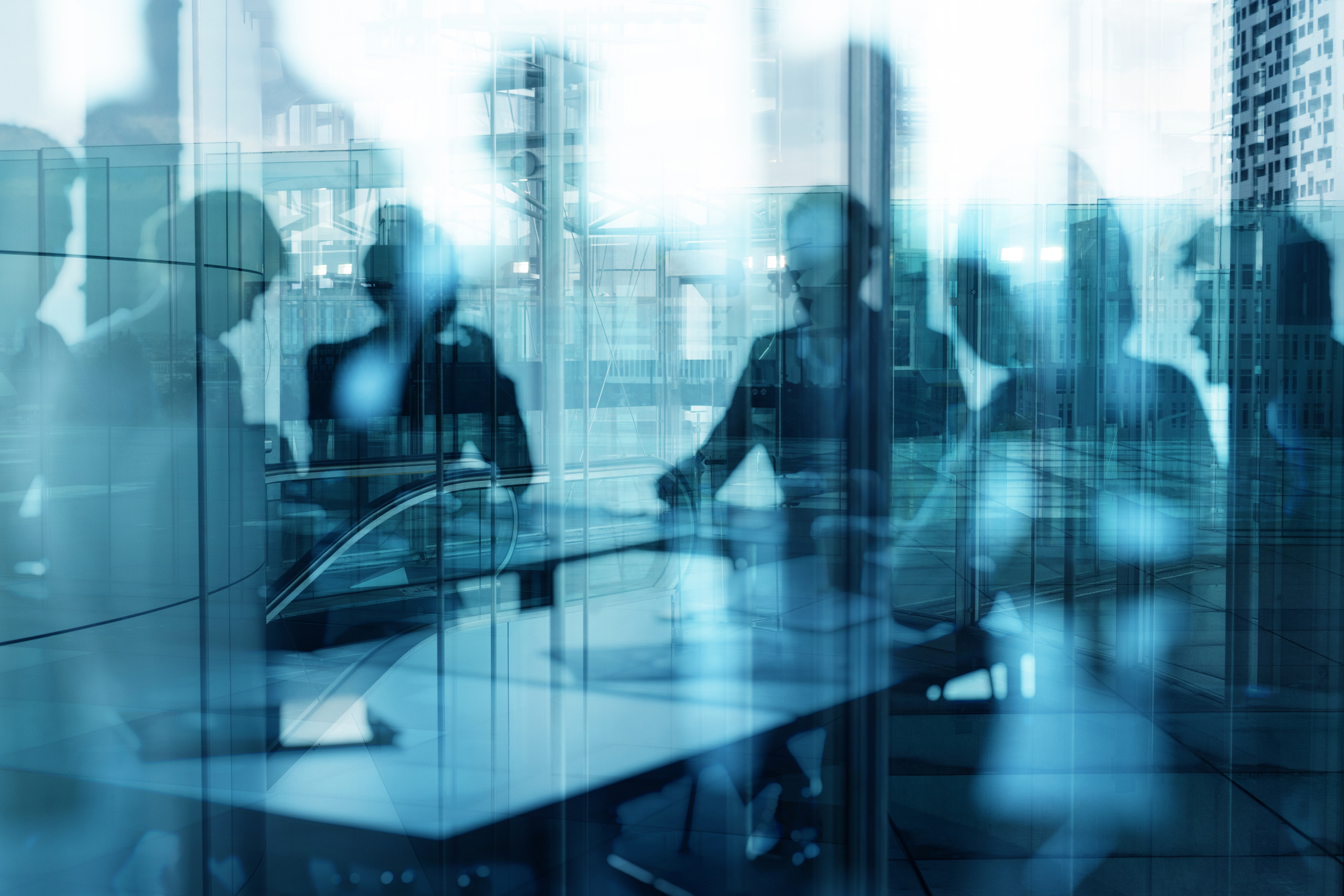 Blue hinted image of a glass wall with reflection of people walking by and an escalator