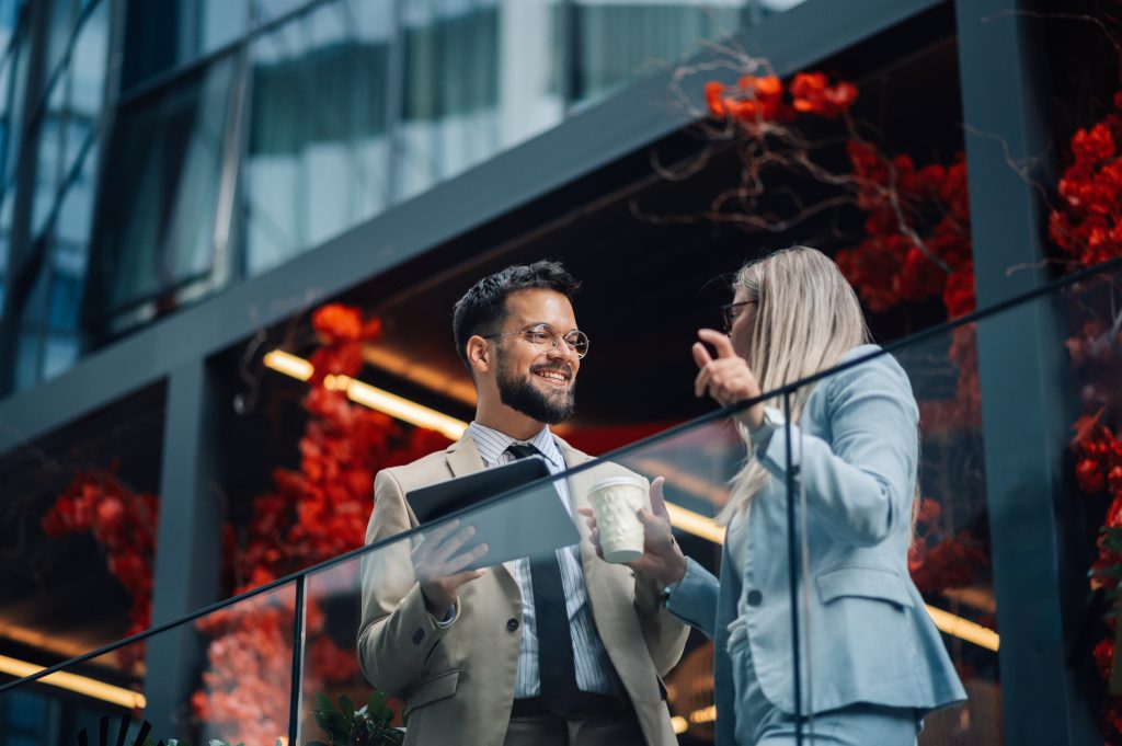 Man and woman standing outside in front of a glass divider talking