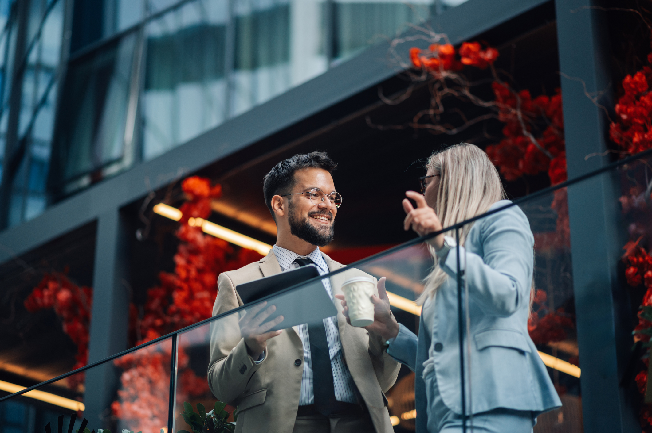 Man and woman standing outside in front of a glass divider talking