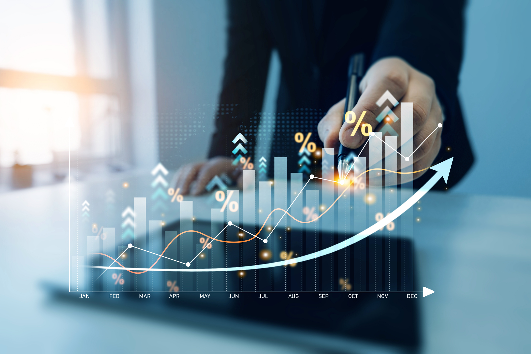 Monthly numbers graph with a mans hand holding a pen to the graph