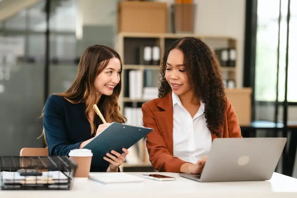 Two young businesswomen collaborate on a Statement of Work.